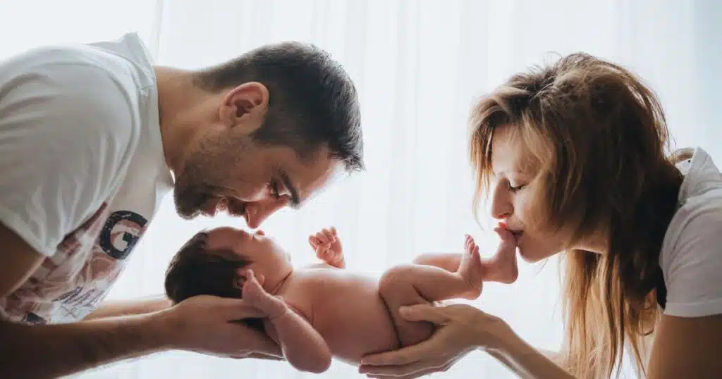 mom and dad kissing baby's head and toes at the same time